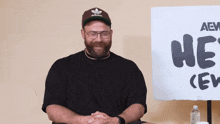a man sitting in front of a sign that says he 's