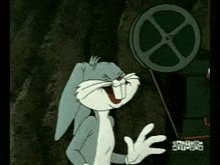 bugs bunny is laughing and waving in front of a movie reel .