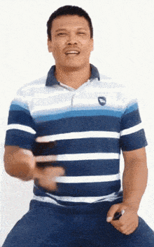 a man wearing a blue and white striped shirt is holding a cell phone