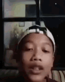 a young boy wearing a hat is making a funny face while sitting on a couch .
