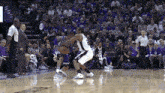 a basketball game is being played in front of a crowd that is purple