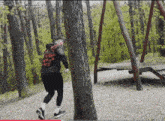 a man standing next to a tree in a park with a swing in the background