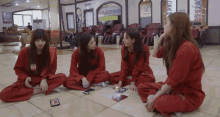 a group of women in red jumpsuits sit on the floor in front of a sign that says ' spa '
