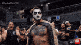 a man with a tattoo on his chest stands in front of a crowd wearing a black shirt that says " bad boy "