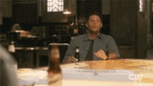 a man is sitting at a table with a bottle of beer
