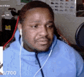 a man wearing ear buds is sitting in front of a microphone with the number 5/700 on the bottom right