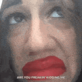 a woman with red lipstick on her lips is making a funny face and says `` are you freakin kidding me '' .