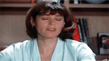 a woman with her eyes closed is sitting at a desk