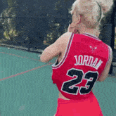 a woman wearing a red jersey with the number 23 on it is holding a basketball .