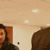 a man in a black jacket is looking at another man in a red jacket