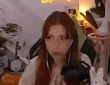 a woman is wearing headphones and looking at the camera while sitting in front of a microphone .