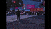 a crowd of people crossing a street in front of a billboard that says valdy