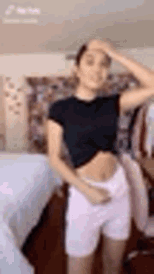 a woman in a black crop top and pink shorts is dancing in a room .
