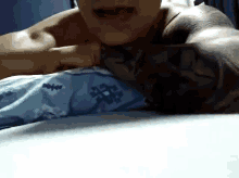 a shirtless man with a tattoo on his arm is laying on a bed .