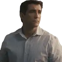 a man in a plaid shirt looks to the side with a serious look on his face