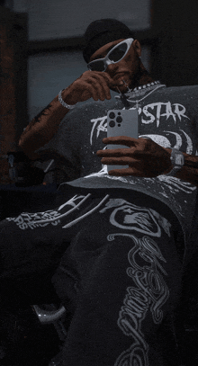 a man wearing sunglasses and a shirt that says tr star is taking a selfie