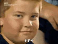 a close up of a young boy 's face with the words `` hey '' written on it .