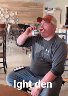 a man sitting at a table drinking from a cup with the words ight den below him
