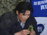 a man in a suit and tie is eating a lettuce sandwich with chopsticks .