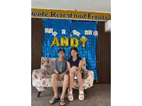 a boy and a girl are sitting on a couch in front of a sign that says " happy birthday andy "