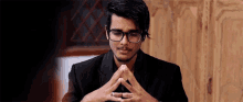a man with glasses and a ring on his finger looks down