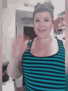 a woman wearing a blue and black striped tank top is smiling