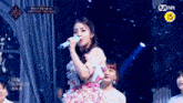 a woman in a floral dress is singing into a microphone .