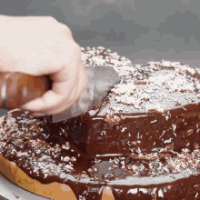 someone is cutting a chocolate cake with a knife