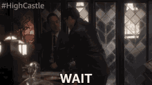 two men are standing in front of a window and one of them is saying wait