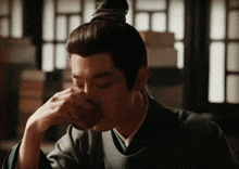 a man with a ponytail is drinking from a cup