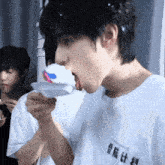 a boy wearing a white shirt with chinese writing on it is eating a cupcake