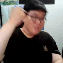 a man wearing glasses and a black shirt is making a funny face .