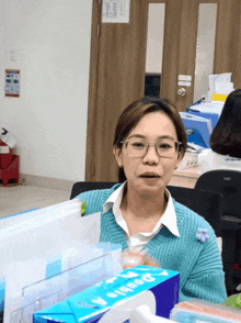 a woman sitting at a desk with a box of double a