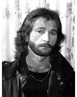 a man with a beard is wearing a leather jacket and a black shirt .