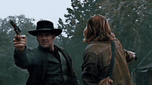 a man in a cowboy hat points a gun at a woman