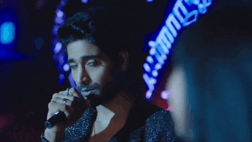 a man singing into a microphone with a woman behind him