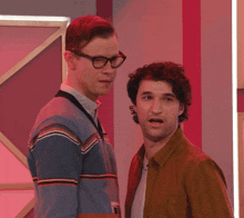 a man wearing glasses is hugging another man in a brown shirt