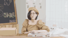 a woman sits at a table with a box and a book that says fragile on it