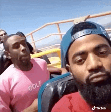 two men are riding a roller coaster together and one of them is wearing a pink shirt .