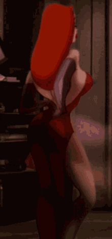 a woman in a red dress and gloves is standing in a dark room