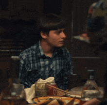 a young man sitting at a table with his hand on his forehead