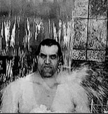 a black and white photo of a man taking a shower .