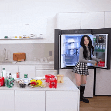 a woman in a plaid skirt is standing in front of a fridge that has a coca cola can in it