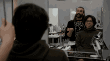 a man wearing a jack daniels sweater looks at his reflection in a mirror