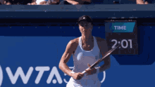 a woman is holding a tennis racquet in front of a sign that says time