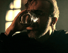 a man with a beard is drinking out of a glass