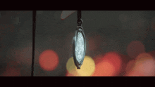 a close up of a watch hanging from a string with a blurry background