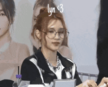 a woman wearing glasses and a necklace has the word lyn < 3 written on her head