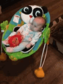 a baby is laying in a bouncer with a panda face