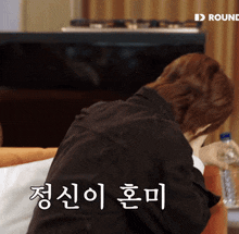 a man sits on a couch with a bottle of water in front of him and the word round is on the bottom
